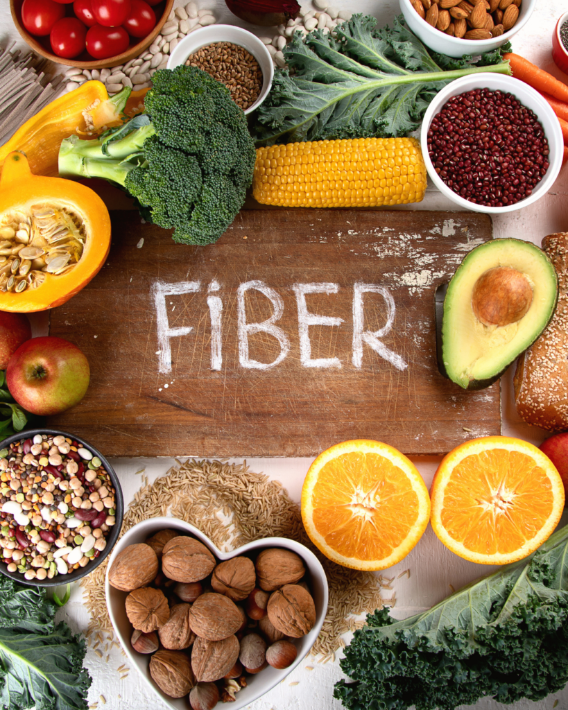 Plate of high-fiber foods including vegetables, whole grains, legumes, and fruit arranged for a balanced meal.